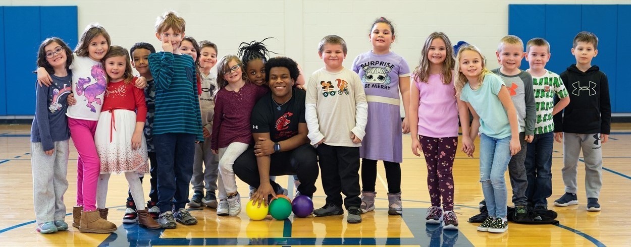 Students pose with physical education teacher during gym class