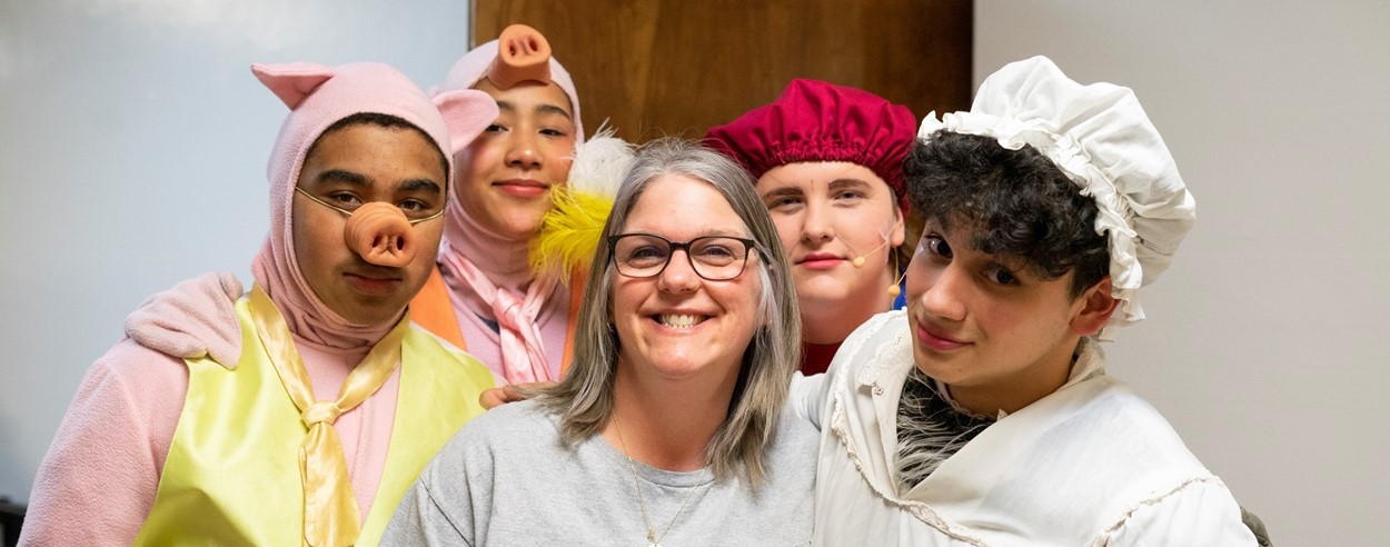 Students in costume stand with teacher before musical performance